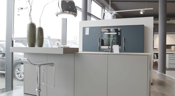 Moderne offene Küche mit Kochinsel, Barhocker und großen Fenstern im Tageslicht.