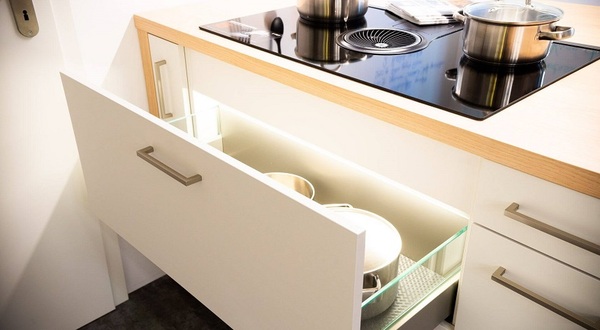 Moderne Küche mit offenem Schubladenschrank, Induktionskochfeld und Töpfen.